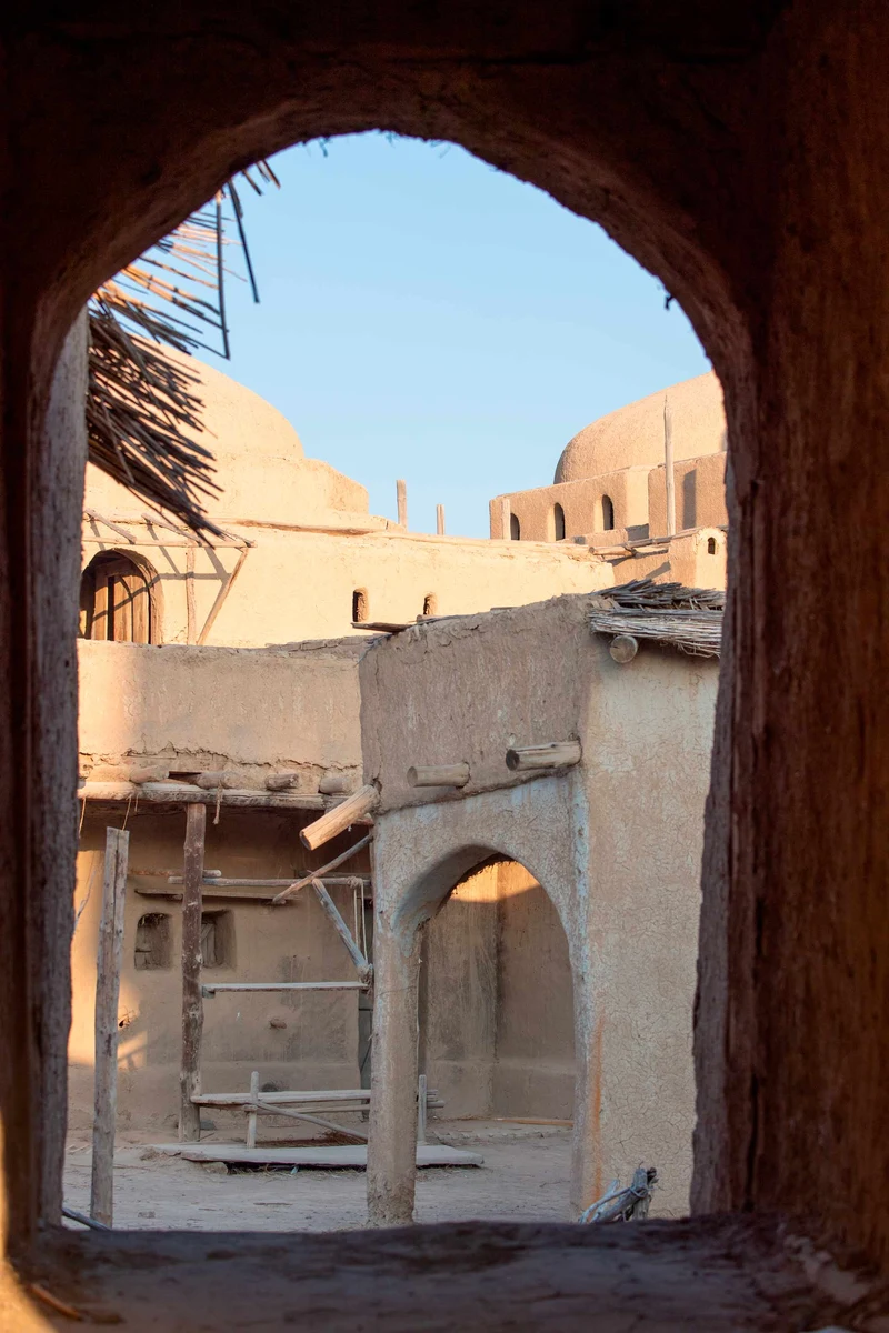 View through a stone archway of mud-brick courtyard buildings with domed roofs